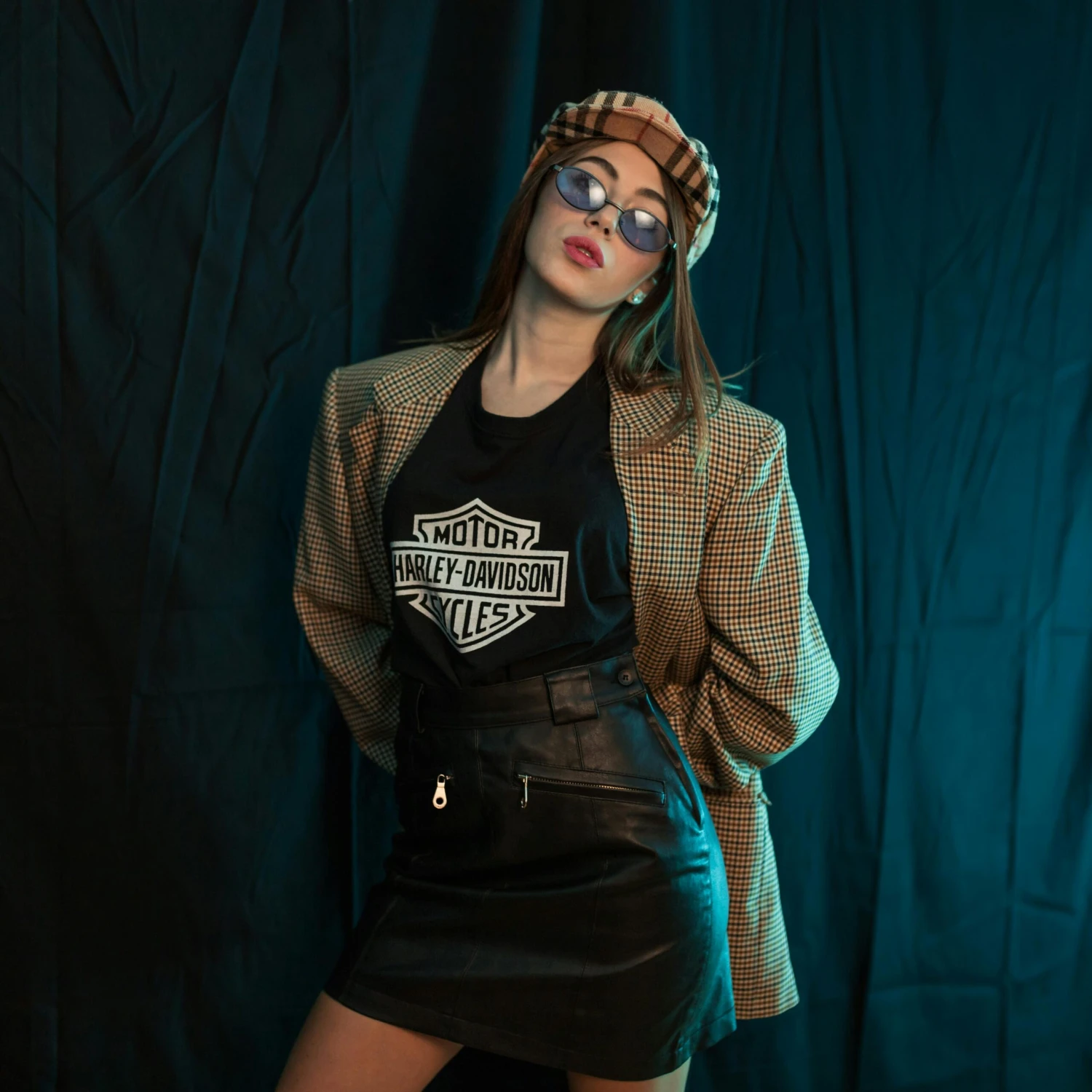 Trendy young woman posing in vintage attire and sunglasses indoors.